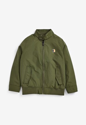 Veste légère verte, fermeture éclair à l'avant, col montant, deux poches latérales, poignets élastiques, avec un petit écusson logo en orange et bleu.