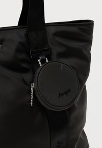 Μαύρη τσάντα ώμου από νάυλον με στρογγυλό θήκη με φερμουάρ που είναι προσαρτημένη με λουρί; λείο υλικό με διακριτική λεπτομέρεια λογότυπου.