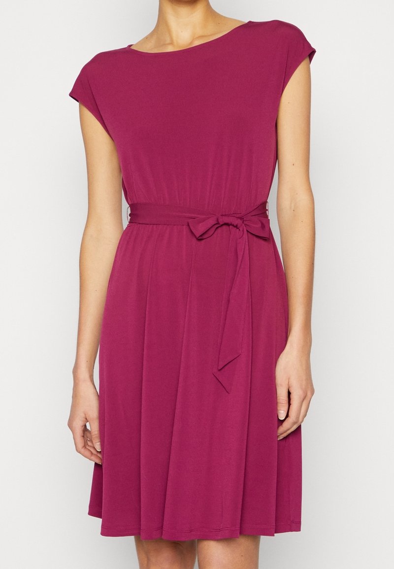 Sukienka magenta do kolan z krótkimi rękawami, okrągłym dekoltem i materiałowym paskiem w talii. Miękka, gładka tekstura z płynącą sylwetką.