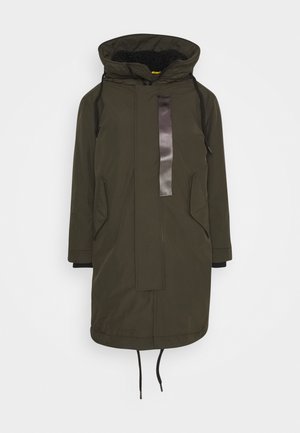 Olivengrøn parka med hætte foret med imiteret pels, to sidelommer, en blank sort frontpanel og snørelukning nederst.