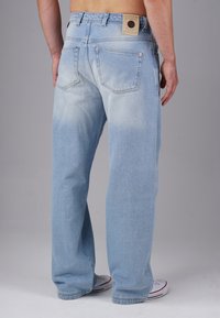 Helle blaue Denim-Jeans mit geradem Bein, verblasster Textur, fünf Taschen und einem markierten Lederpatch am hinteren Bund.