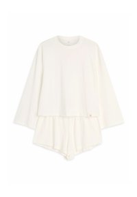 White loungewear set featuring a long-sleeve top and shorts. Soft fabric, relaxed fit with a layered design and small logo detail.