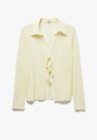 Blusa a maniche lunghe gialla chiara con collo a camicia e chiusura a fiocco sul davanti. Tessuto morbido con dettagli a bordi ondulati.
