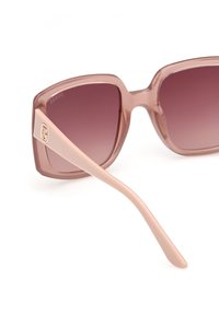 Ochelari de soare cu gradient roz, cu rame pătrate, din material roz transparent, și brațe roz deschis, având un accent cu logo auriu.
