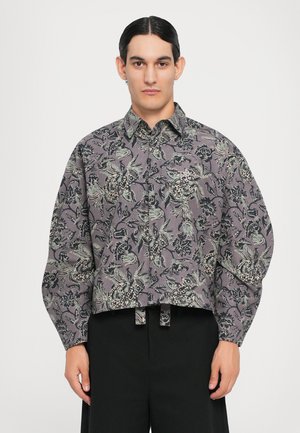 Geknöpftes, kurzes Hemd aus grauem Stoff mit floralen und blattartigen Mustern in Schwarz und Grün. Verfügt über eine Knopfreihe vorne und lockere Ärmel.