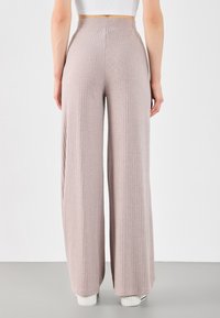 Helle lila, gerippte, weit geschnittene Hosen mit hoher Taille, aus weichem Stoff. Verfügt über einen glatten Taillenbund und fließt bis zum Boden.