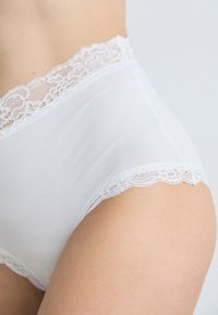 White high-waisted underwear with a lace trim along the waist. Smooth fabric texture, soft finish, and a classic cut.