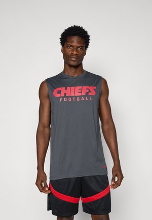 Graues ärmelloses Shirt mit "CHIEFS FOOTBALL" in fettem roten Schriftzug; kombiniert mit schwarzen Shorts mit roten Akzenten und einem strukturierten Design.