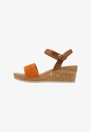 Keilabsatzsandale mit einem braunen Lederknöchelriemen und einer Vorderseite aus orangefarbenem Wildleder. Plattform mit Korktextur und Gummisohle für besseren Halt.