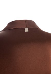 Colletto di camicia in satin marrone con una texture liscia, dotato di un dettaglio logo argentato sul retro. Design semplice con un taglio classico.