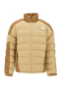 Veste en duvet beige avec des accents caramel. Conçue avec un col montant, une fermeture éclair à l'avant et une texture matelassée horizontale. Logo sur la poitrine.
