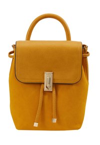 Żółty plecak z eko skóry o strukturalnym wykończeniu, z klapą zamykaną na zatrzask, złotymi elementami i dwoma przednimi paskami do regulacji.