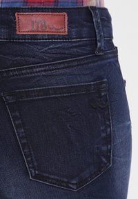 Mörkblå denimjeans med en läder LTB-etikett, detaljerad sömnad och en bakficka med ett präglat mönster.