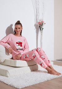 Rózsaszín pizsama szett hosszú ujjú pólóval, amelyen egy jegesmedve grafikája és a "Sweet Dream" felirat található; a nadrágot pedig ismétlődő medveminták díszítik.