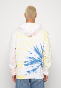 Felpa bianca con un motivo tie-dye nei colori blu, giallo e rosa. Il design presenta un cappuccio con lacci e polsini a coste.