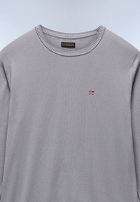 Maglione grigio chiaro a maniche lunghe con scollatura rotonda, orlo a coste e un piccolo accento ricamato della bandiera norvegese sul petto.