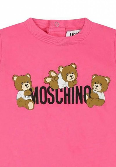 Rosa Baumwoll-T-Shirt mit drei Cartoon-Teddybären, die weiße Hemden tragen, und dem Wort "MOSCHINO" in fetter schwarzer Schrift darunter.