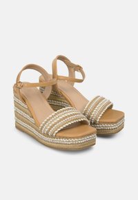 Hakken sandalen met een tan faux leren bovenwerk, gevlochten jute en crème accenten, gestructureerde banden en een gladde voetbed.