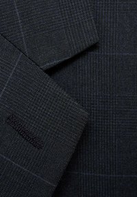 Dark blue textured fabric with a subtle plaid pattern, featuring a close-up of a blazer's lapel and shoulder details, with a sleek finish.