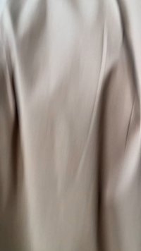 Lichtbeige stof met een gladde textuur, voorzien van subtiele plooien en een zachte val. Het ontwerp oogt eenvoudig en minimalistisch.