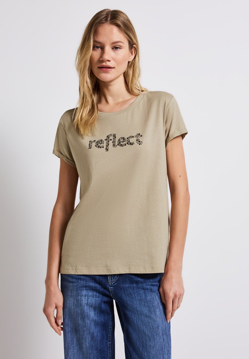 Camiseta de manga corta color caqui con la palabra "reflect" impresa en un diseño texturizado. Material de algodón suave con un ajuste holgado y cuello redondo.