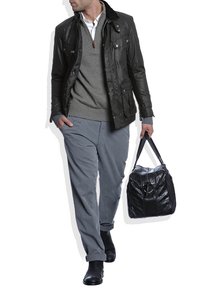 Czarna skórzana kurtka na szarym swetrze, szare spodnie i czarne buty; trzyma czarną skórzaną torbę z okrąłym akcentem.