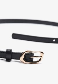 Cinturón de cuero negro con hebilla de metal dorado pulido. Presenta una textura suave y un diseño elegante. Ajustable con múltiples agujeros.