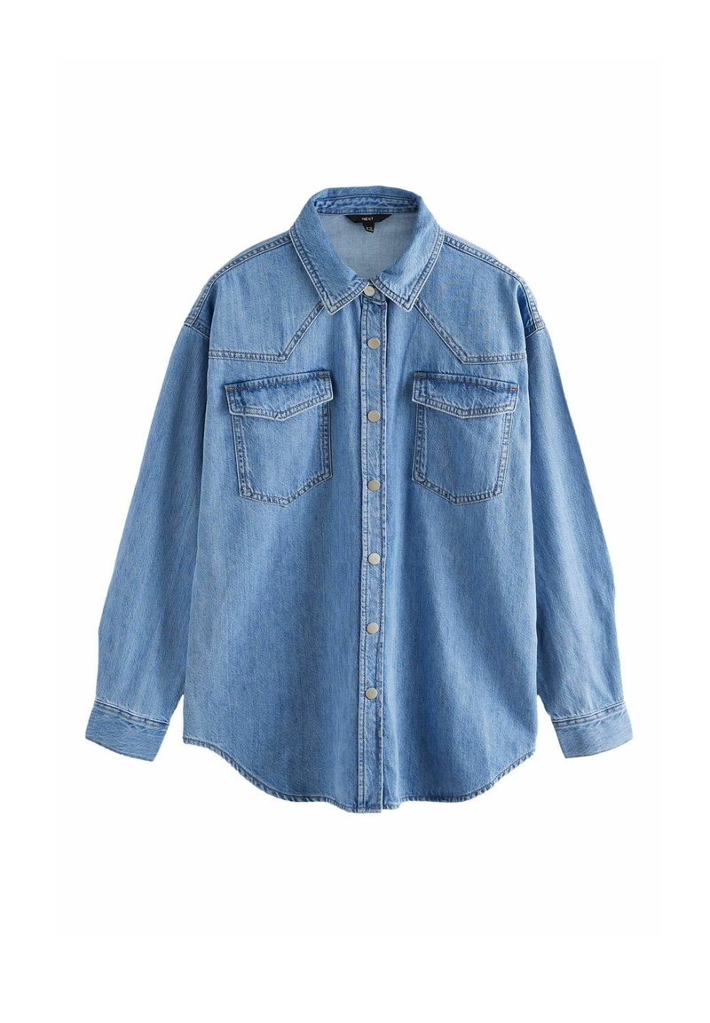 Camisa de denim azul claro con cuello clásico, mangas largas, dos bolsillos en el pecho y botones plateados, con un dobladillo ligeramente curvado.