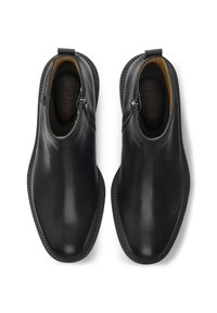 Paire de bottines en cuir noir avec fermetures éclair latérales et semelles intérieures de marque, vues de dessus sur fond blanc.