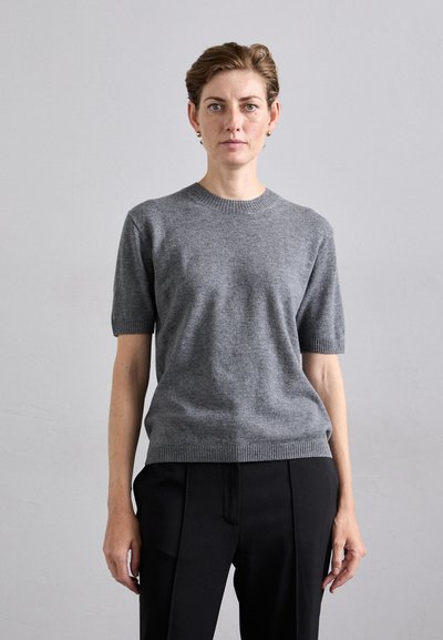 Pull en tricot gris à manches courtes avec un col et des poignets côtelés, doté d'une texture lisse. Associé à un pantalon noir élégant.