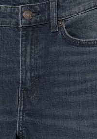 Tmavomodré džínsy z denimu s hladkým povrchom, s prednou vreckom, kovovým gombíkom a viditeľným prešívaním pozdĺž švov.