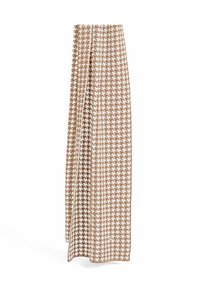 Tkanina w brązowo-biały wzór w jodełkę, zwisająca i falująca, ukazująca gładką fakturę i prostokątny kształt.