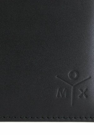 Surface en cuir noir avec une figure humaine minimaliste en relief et les lettres "M" et "X" près du bord cousu.