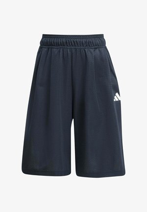 Niño con gorra negra de Adidas, camiseta negra de Adidas holgada, pantalones cortos negros con rayas blancas, calcetines negros con rayas blancas y zapatillas blancas de Adidas.