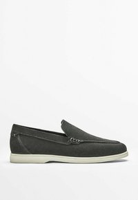 Mocassin slip-on en daim gris foncé avec semelle en caoutchouc blanche et détails de couture discrets, présenté de profil sur fond blanc.