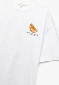 Hvid bomulds t-shirt med et lille grafik af en appelsinskive og tekst. Korte ærmer, rund hals og løs pasform med en glat tekstur.