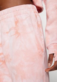 Lys rosa tie-dye sweatshirt og joggebukser, med elastisk midjebånd og sidelommer, myk tekstur og løs passform.