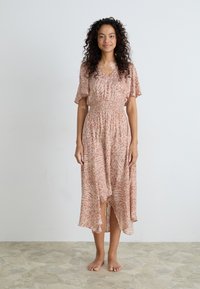 Vestido rosa de estampado con mangas cortas, escote en v y dobladillo asimétrico; hecho de un material ligero con una textura fluida.