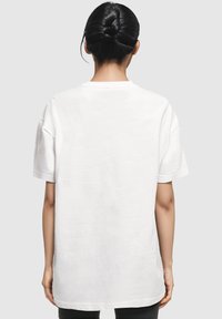 Witte, oversized katoenen t-shirt met korte mouwen, ronde halslijn en een rechte zoom. Gladde textuur, geen zichtbare patronen of accenten.