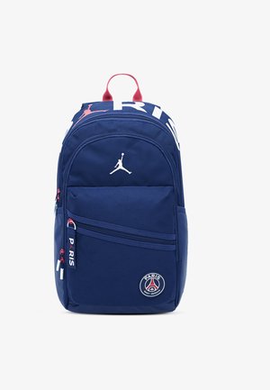 Rucsac albastru marin din material textil, cu logo Jordan, două compartimente cu fermoar și un patch Paris Saint-Germain pe față. Accente roșii pe fermoare.
