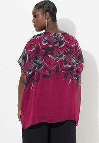 Gennemsigtig magenta bluse med et blomsteragtigt sort og gråt mønster, korte ærmer, rund halsudskæring og et løst, strømmende design.