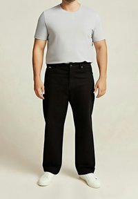 Camiseta gris de manga corta combinada con pantalones rectos negros y zapatos slip-on blancos, con un diseño sencillo y una textura suave.