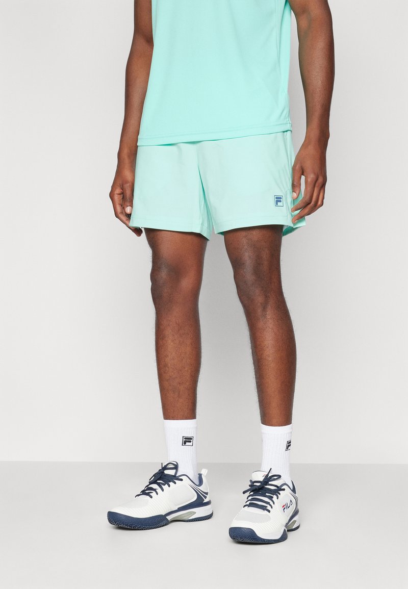 Világos mentazöld sportnadrág és hozzáillő tanktop, logo emblémával. Fehér zoknikkal és fehér-navy sportcipővel viselve.