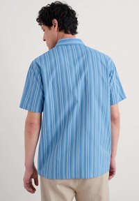 Camisa de manga corta con cuello en azul claro y rayas verticales blancas. Fabricada con un material ligero y de textura suave, que ofrece un ajuste relajado.