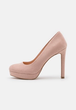 Beige ruskind platform højhælede pumpe med lukket rund snude og slank stilet hæl på hvid baggrund.