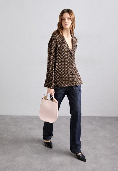 Brunmønstret bluse med lange ærmer og lommer, kombinert med mørke denimjeans. En myk rosa håndveske og spisse sorte sko fullfører antrekket.