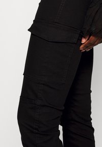 Zwarte cargobroek gemaakt van een katoenmix, met zijzakken, gedetailleerde stiksels, slim fit en een gladde textuur.