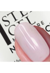 Smalto per unghie in gel trasparente e lucido su un'unghia scolpita, con un colore rosa chiaro e una leggera brillantezza, su uno sfondo chiaro.