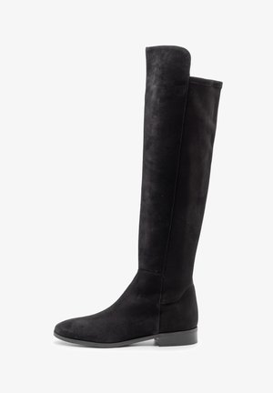 Stivale sopra il ginocchio in suede nero con punta arrotondata e suola piatta. Texture liscia e design sagomato; dettagli di cuciture minimi.