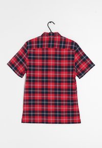 Košile s krátkým rukávem s kostkovaným vzorem v červené a námořnické modři, s límečkem na knoflíky a detailem na zadním díle. Bavlněný materiál s poutkem na zavěšení.
